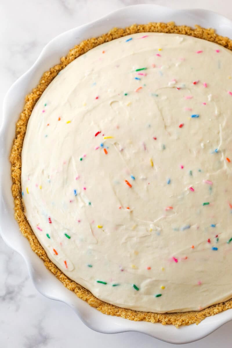 no churn cake batter ice cream added to prepared crust in white ruffle pie plate
