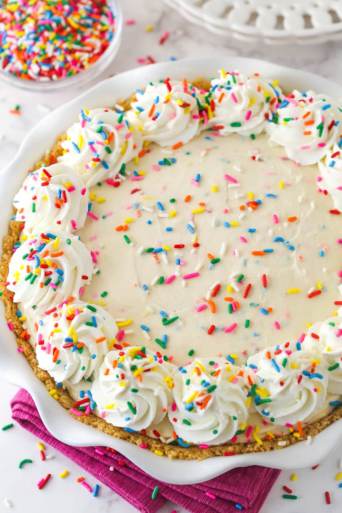finished cake batter ice cream pie on marble background with bright pink napkin underneath