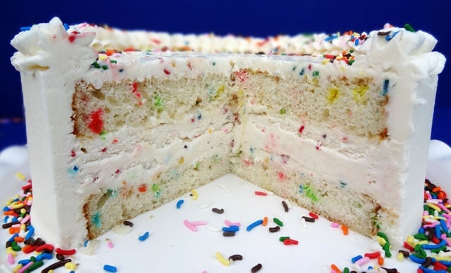 Side view of a cut Funfetti Cake Batter Ice Cream Cake so you can see the ice cream and sprinkles in the middle