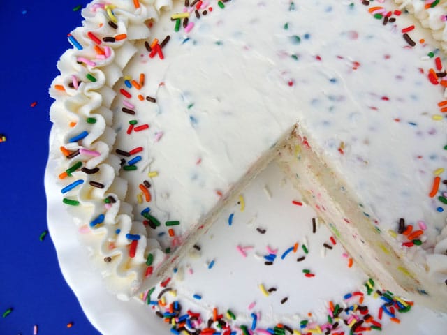 Top view of a whole Funfetti Cake Batter Ice Cream Cake With Rainbow Chip Icing with a slice missing