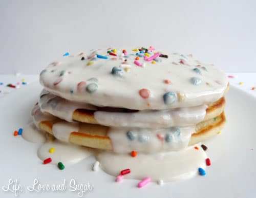 A stack of Funfetti Pancakes with sprinkle icing syrup