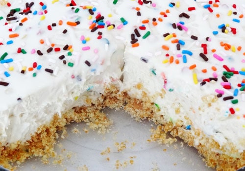 Close up of a Funfetti Ice Cream Pie topped with sprinkles and a big slice missing