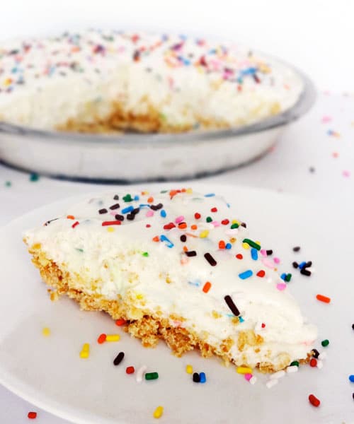 A slice of Funfetti Cake Batter Ice Cream Pie on a white plate with sprinkles 
