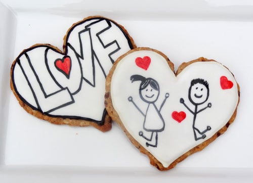 Two Heart-Shaped Oatmeal Cut-Out Cookies Decorated with Hearts and Stick Figures