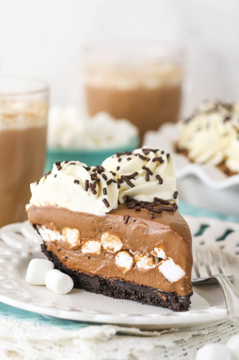 This Baileys Hot Chocolate Ice Cream Pie is an easy no bake dessert that combines all your favorite cozy winter flavors into one pie! slice of Baileys Hot Chocolate Ice Cream Pie on white plate