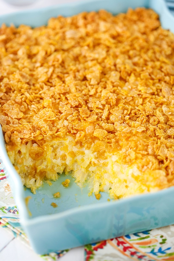 A cheesy hashbrown casserole inside of a light blue baking dish on a dining table
