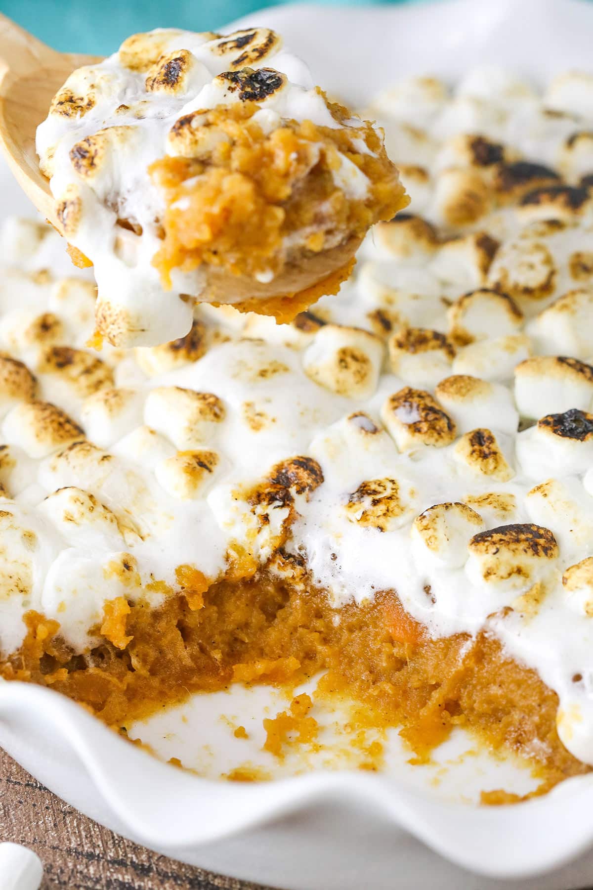 This classic sweet potato casserole recipe is flavored with brown sugar and fall spices, then covered with gooey toasted marshmallows! Sweet potato casserole in a baking dish with a scoop being taken out.