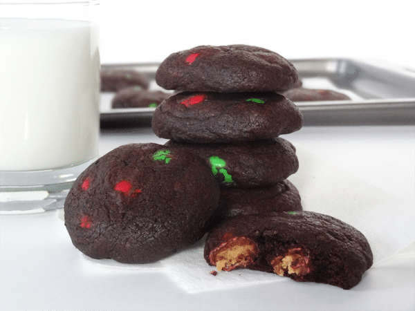 Chocolate Peanut Butter M&M Cookies are stacked next to a glass of milk