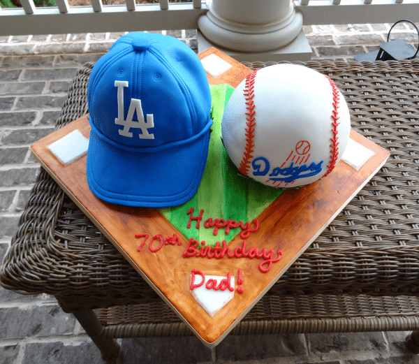 A Baseball Field Cake Stand Holding a Baseball Birthday Cake and a Dodgers Birthday Hat Cake