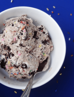 A bowl of birthday cake ice cream with a metal spoon inside