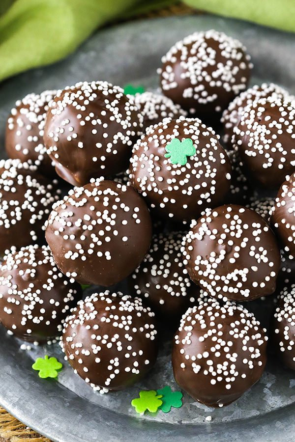 A large plate full of no-bake Baileys cookie balls in front of a green dish towel