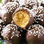 No-bake Baileys cookie balls piled onto a plate with one missing a bite to reveal the cookie inside the chocolate coating