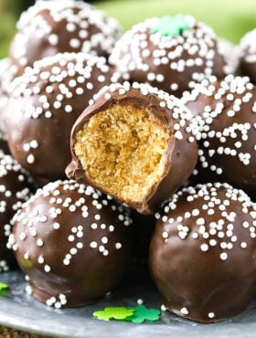 No-bake Baileys cookie balls piled onto a plate with one missing a bite to reveal the cookie inside the chocolate coating