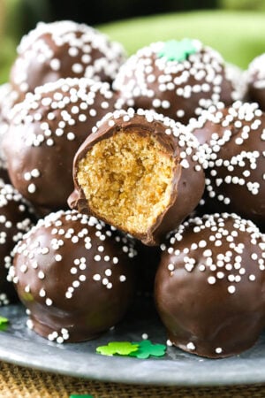 No-bake Baileys cookie balls piled onto a plate with one missing a bite to reveal the cookie inside the chocolate coating