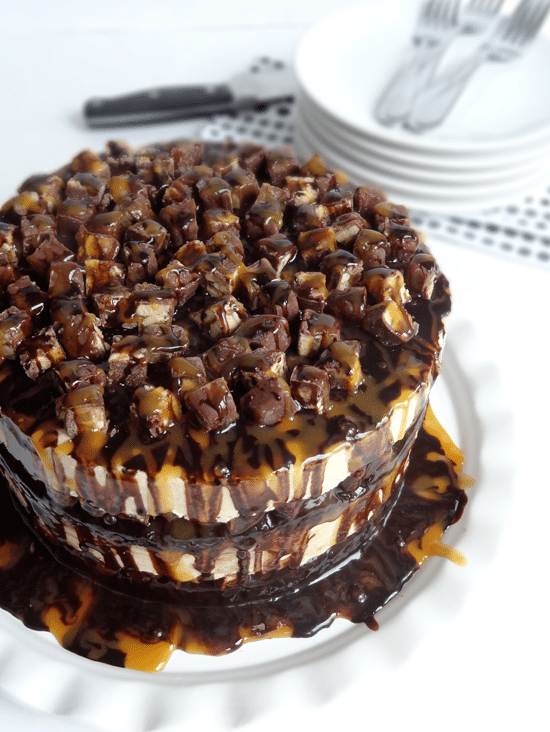 A Peanut Butter Brownie Ice Cream Cake Topped with Chopped Snickers, Caramel Sauce and Chocolate Sauce