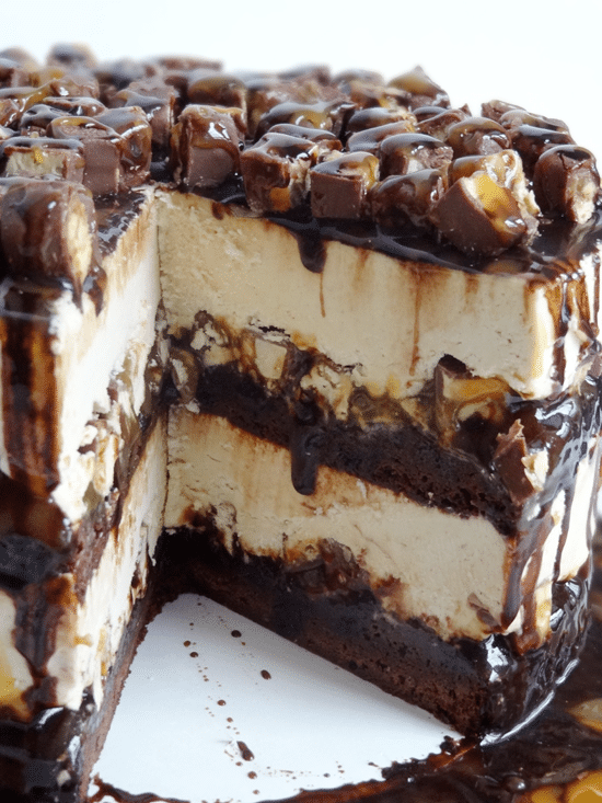 Snickers Peanut Butter Brownie Ice Cream Cake with a big slice missing
