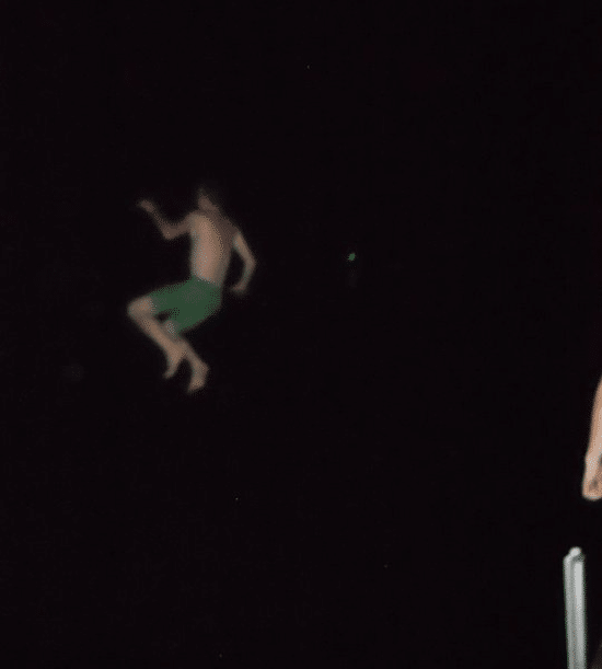 A man dock jumping in the dark