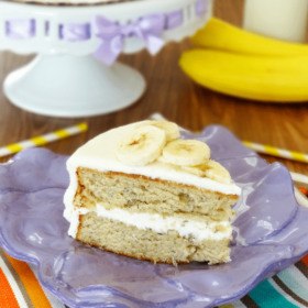 A piece of banana cake on a clay plate with the remaining cake behind it