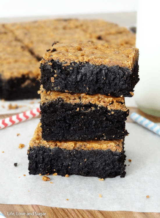 Side view of three fudgy brownies with Butterfinger crust stacked on top of each other