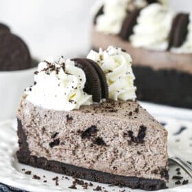 A slice of no bake Oreo cheesecake on a plate drizzled with chocolate sauce.