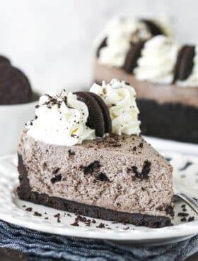 A slice of no bake Oreo cheesecake on a plate drizzled with chocolate sauce.