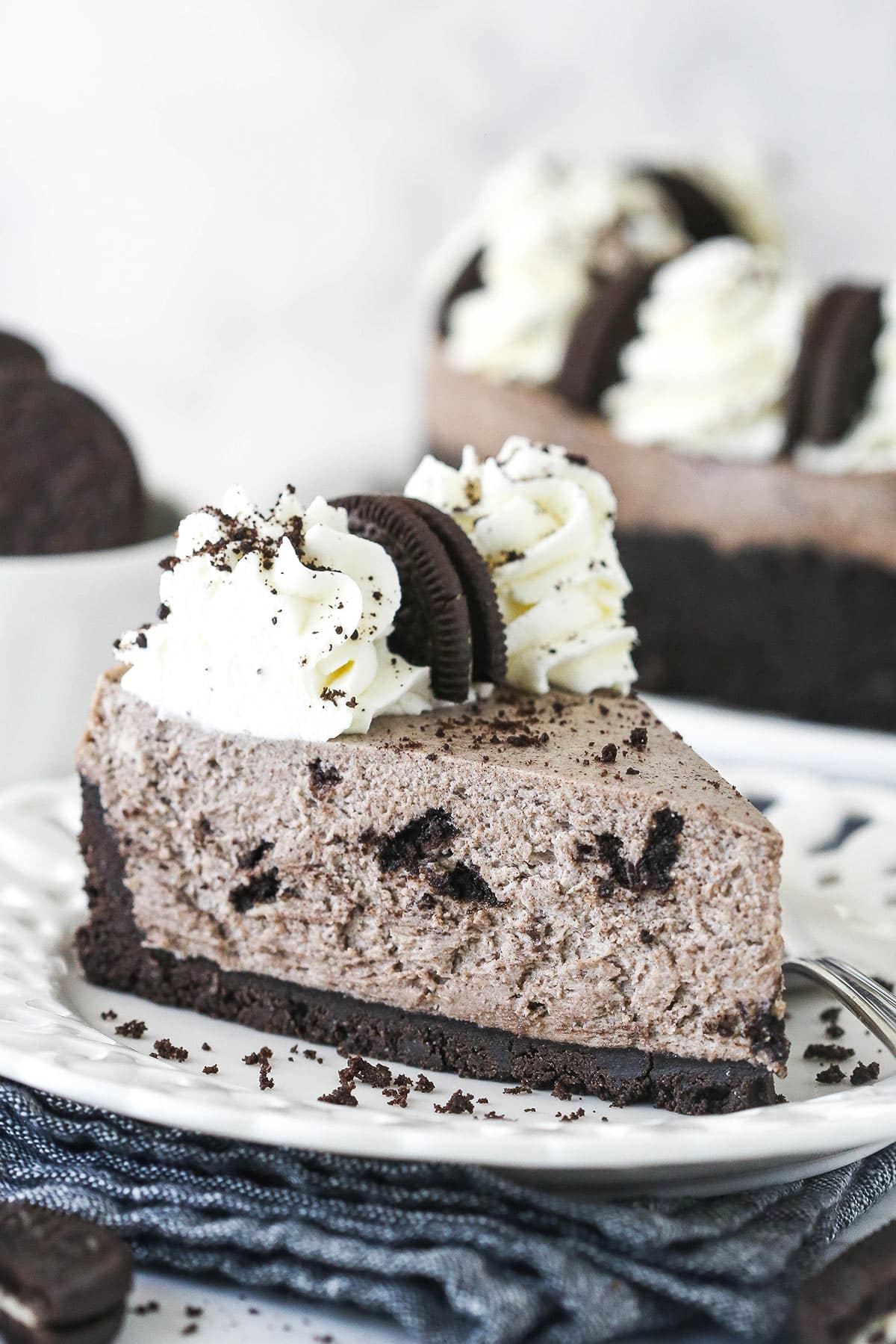 A slice of no bake Oreo cheesecake on a plate drizzled with chocolate sauce.