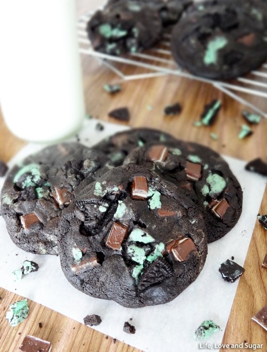 Double Mint Chocolate Cookies piled on white paper with Oreo and Andes Mint crumbs around them