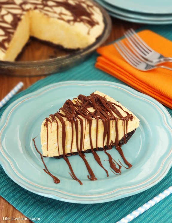 A piece of pumpkin ice cream pie on a plate beside two forks on a napkin