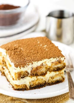 A piece of authentic Tiramisu on a white plate with a fork