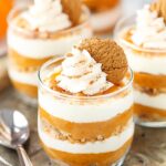 A close-up shot of three no-bake pumpkin pies topped with whipped cream and gingersnap cookies