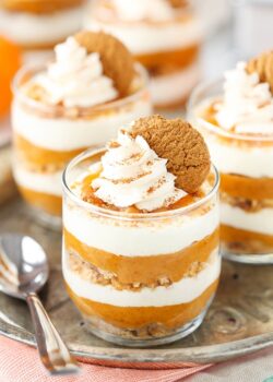 A close-up shot of three no-bake pumpkin pies topped with whipped cream and gingersnap cookies