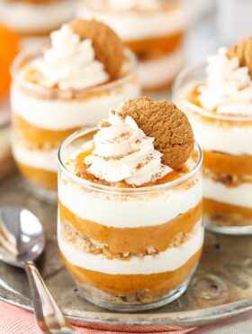 A close-up shot of three no-bake pumpkin pies topped with whipped cream and gingersnap cookies