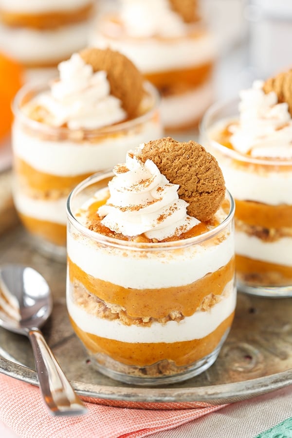 A close-up shot of three no-bake pumpkin pies topped with whipped cream and gingersnap cookies