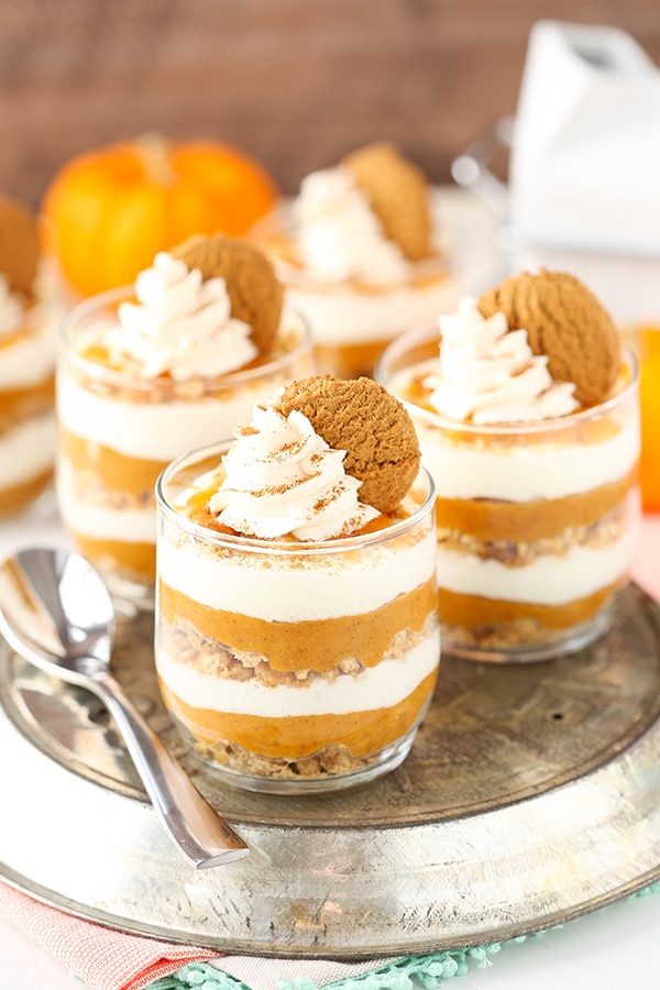 Three glasses filled with layered pumpkin pie with a pumpkin in the background