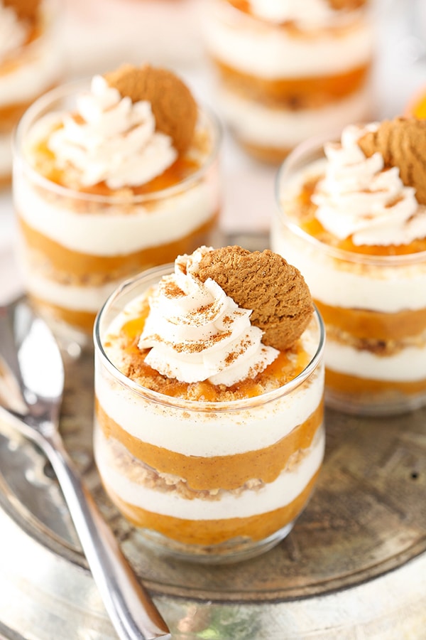 A pumpkin pie in a jar on top of a serving platter with two other pies and one spoon