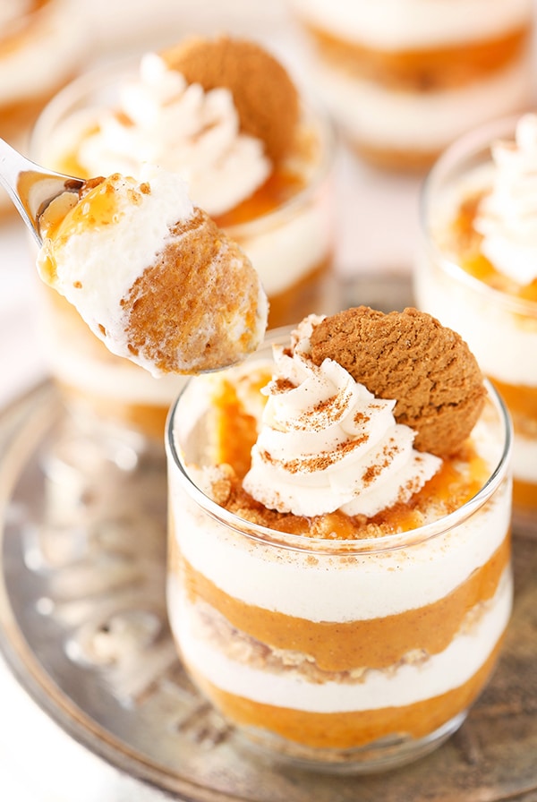 A spoon scooping up a bite of pumpkin pie from a jar with all three layers on display