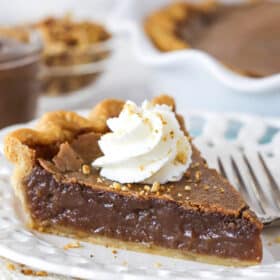 slice of chocolate hazelnut chess pie on a white plate with full pie in background