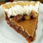 A slice of chocolate hazelnut chess pie with rolos on a white plate