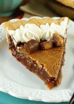 A slice of chocolate hazelnut chess pie with rolos on a white plate