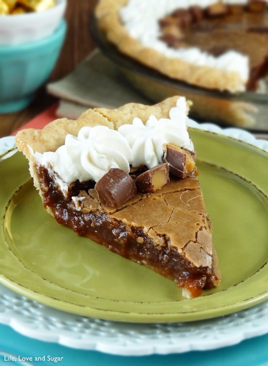 A slice of chocolate chess pie topped with whipped cream and Rolos sits on a green plate