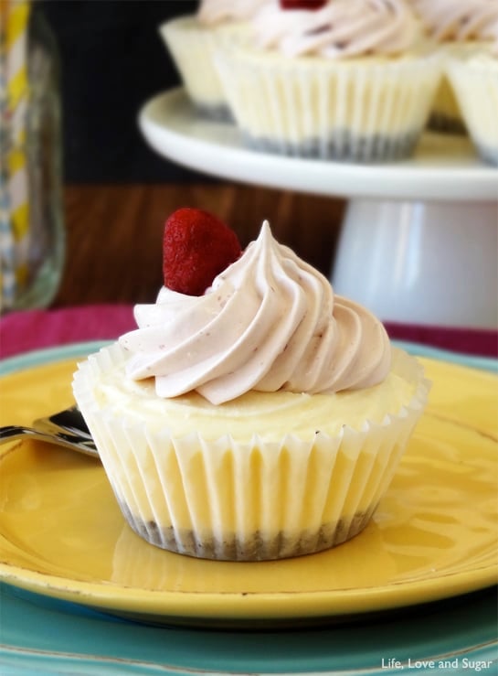 A Raspberry Cheesecake Ice Cream Cupcake with pink whipped cream and a raspberry on top