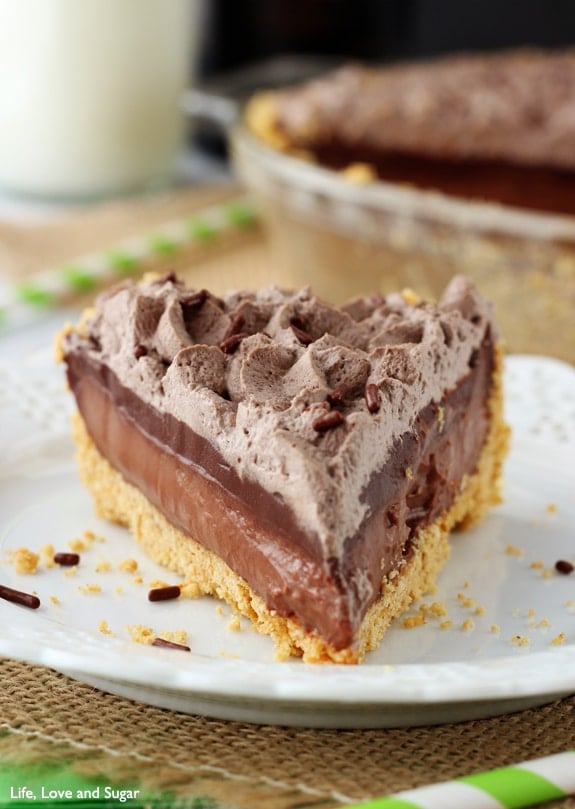 A slice of Chocolate Pie with layers of chocolate filling, ganache and whipped cream