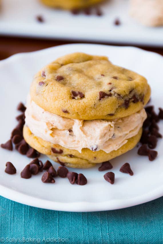 Close up of a Chocolate Chip Cookie Dough Sandwich on a small white plate surrounded with mini chocolate chips.