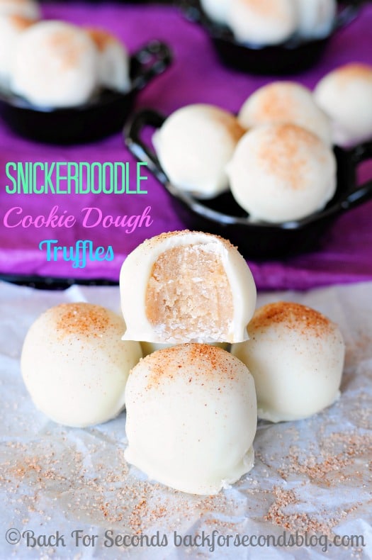 A pile of Snickerdoodle Cookie Dough Truffles with a bite removed from the top truffle to show center.