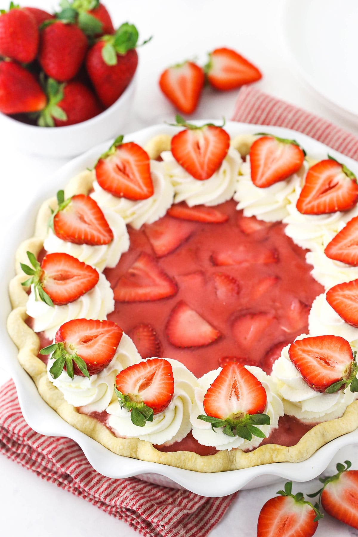 A homemade berry pie inside of a pie plate on top of a striped kitchen towel