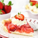 A piece of homemade berry pie on a plate with the remaining pie behind it