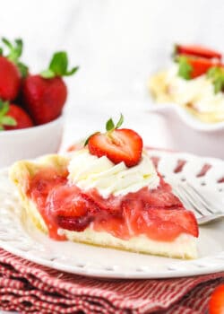 A piece of homemade berry pie on a plate with the remaining pie behind it