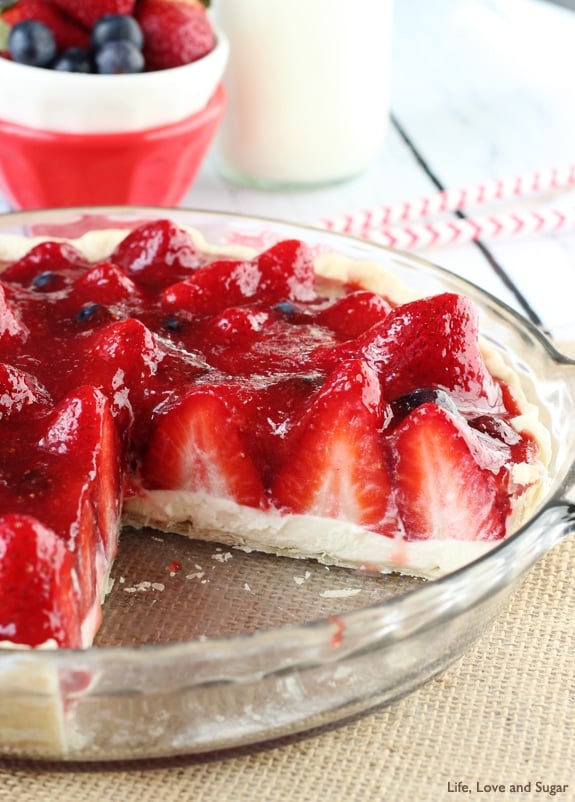 A Strawberry Cream Pie in a clear dish with a slice missing