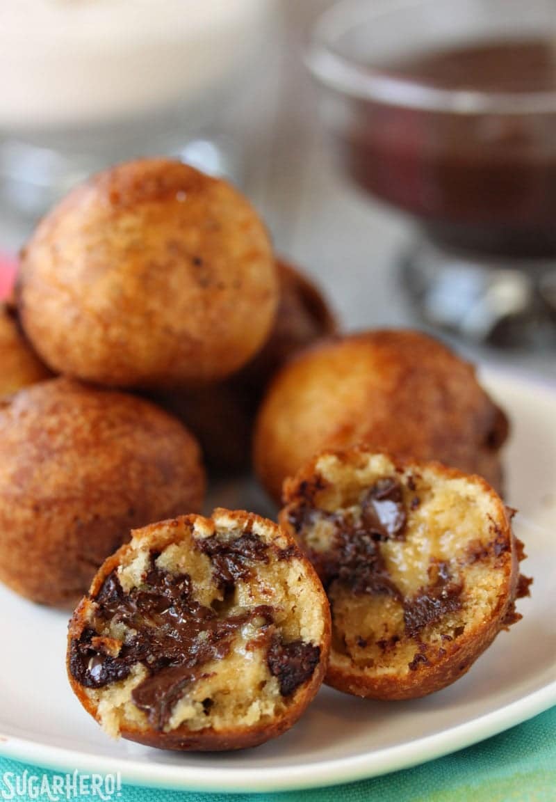 A pile of deep fried cookie dough balls with one broken open to see the center.
