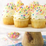 vanilla cupcakes with multicolored sprinkles on wood and marble cake stand
